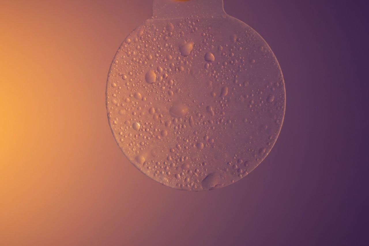 A steamy shower scene with a hydrogel eye shield catching the warm light